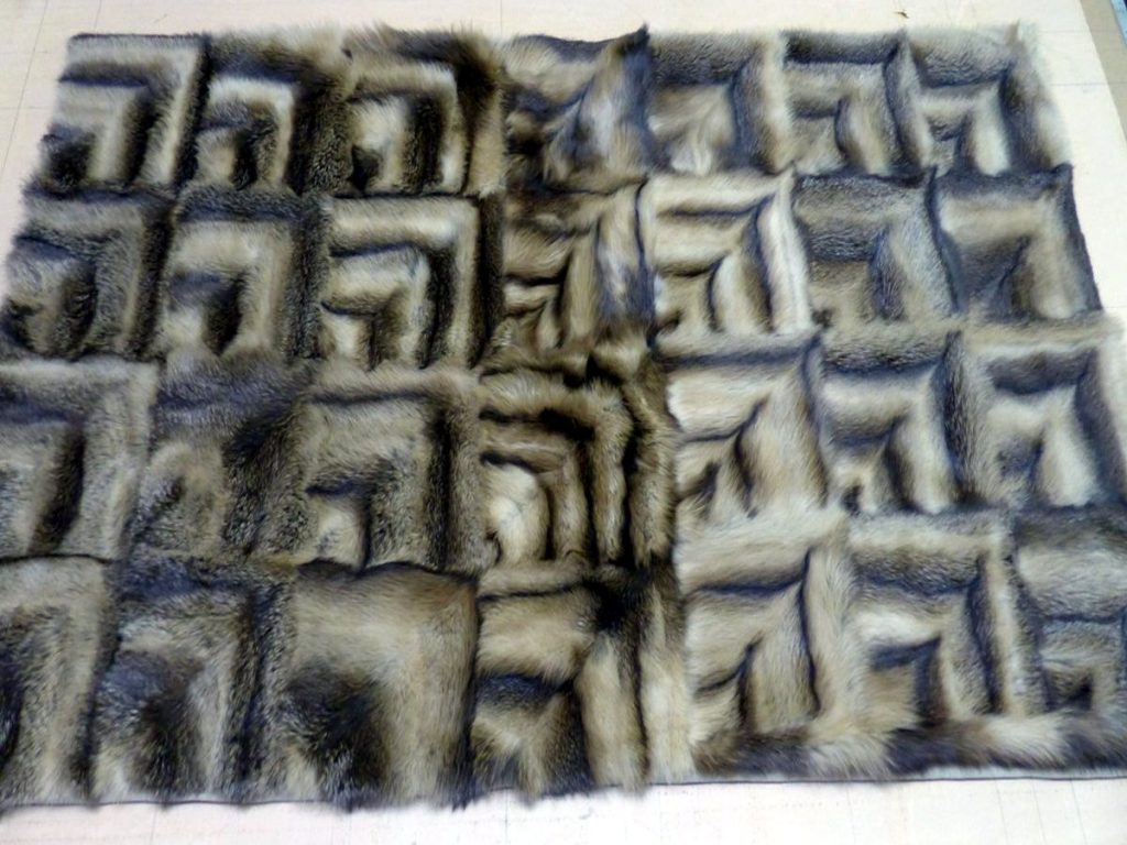 Der Mantel wurde in 56 gleichschenklige Dreiecke geschnitten. Die Dreiecke wurden zu 28 spiegelgleichen Quadraten zusammengefügt.